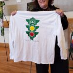 Kathleen holds up a long-sleeved T-shirt with the Tipperary Hill traffic signal (the colors are reversed)